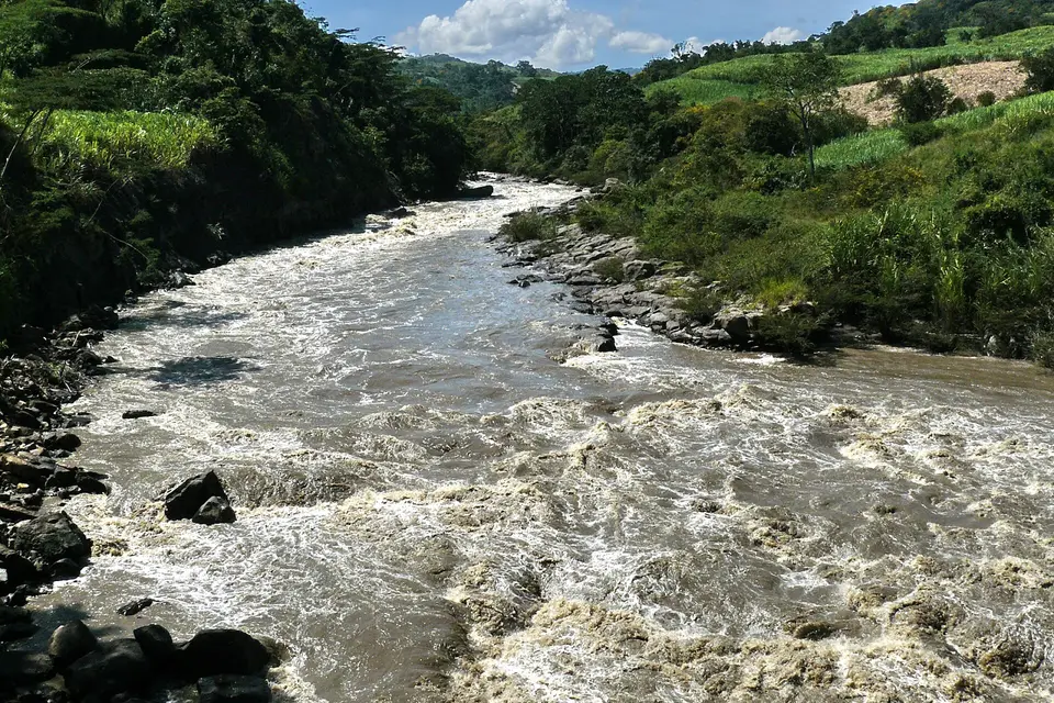 Wide brown rapids on the Río Suárez between green hills.