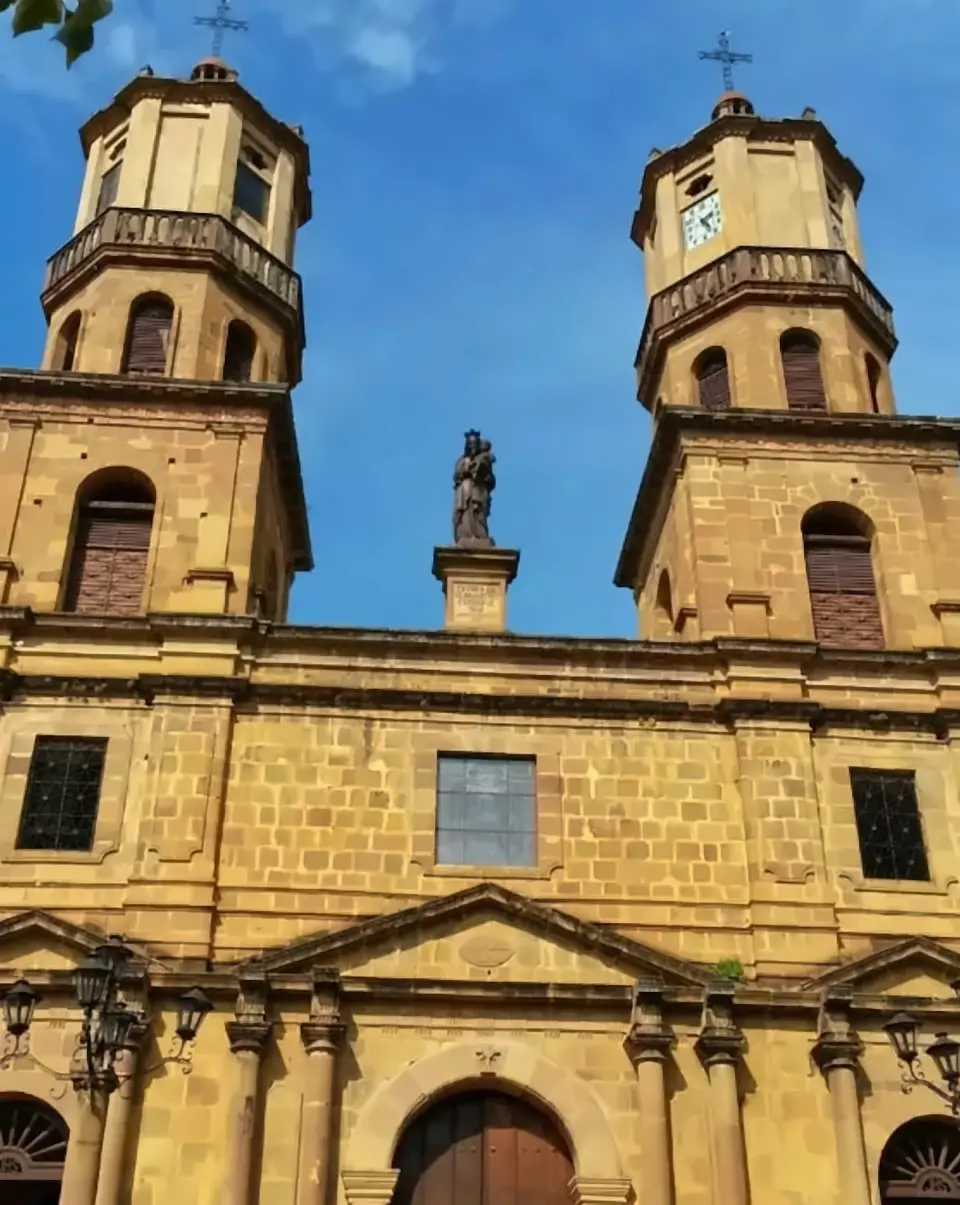 The twin bell towers of San Gil’s Catedral de la Santa Cruz, honey-coloured stone against a deep blue sky.